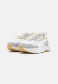 Sneakers bianchi e grigio chiaro realizzati in materiali scamosciati e in rete, dotati di una suola ammortizzata, design con lacci e accenti di branding sottili.