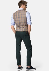 Brązowa kamizelka w kratkę z niebieskimi akcentami, zestawiona z zielonymi spodniami i czarnymi butami. Bawełnowy materiał o gładkiej fakturze, klasyczny krój.