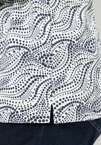Kurzärmliges Hemd mit einem navyblauen und weißen Wirbelpunktmuster, aus leichtem Stoff mit feiner Textur und seitlichem Schlitz.