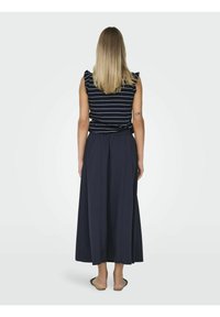 Jupe maxi bleu marine avec taille élastique, associée à un haut rayé bleu marine et blanc avec des manches froncées. Vue de dos présentée.