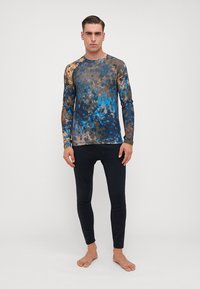 Tricou athletic cu mâneci lungi, prezentând un model abstract multicolor în nuanțe de albastru, maro și negru, asortat cu colanți negri uni.