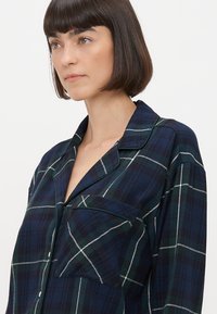 Μπλε μελανζέ πουκάμισο με πράσινες και λευκές λεπτομέρειες, με γιακά, μπροστινή τσέπη και κουμπάκια. Μαλακό ύφασμα με άνετη εφαρμογή.