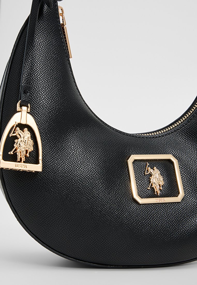 Un sac à bandoulière en cuir noir avec une surface texturée, des accents en doré, une fermeture éclair et un détail de logo emblématique.