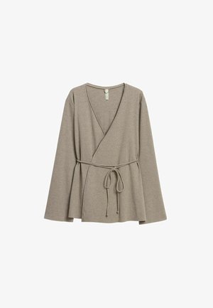 Beige geribbelde wikkeltrui met lange mouwen, V-hals en een ceintuur in de taille. Zachte textuur, losse pasvorm en uitlopende zoom.