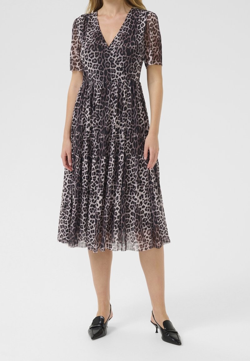 Robe à imprimé léopard avec décolleté en V, manches courtes transparentes et jupe à volants. Fabriquée en tissu léger, présentant une palette de couleurs noir et beige.