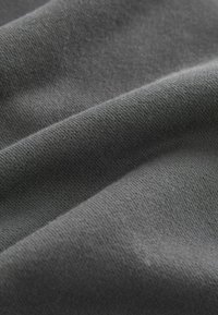 Grauer Stoff mit einer glatten, weichen Webart, die subtile Variationen in Farbe und Tiefe zeigt und dabei seine leichte und biegsame Natur hervorhebt.