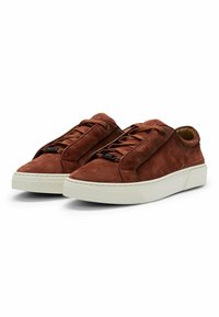 Brown suede sneakers with flat laces, featuring a white rubber sole, rounded toe, and side accents. No visible branding on the exterior.