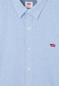 Camicia azzurra chiaro con bottoni, realizzata in tessuto strutturato, con colletto, bottoni bianchi e un piccolo logo Levi's rosso sul petto a sinistra.