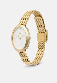 Reloj con tono dorado, correa de malla y caja redonda. La esfera blanca presenta marcadores horarios simples y un centro texturizado. Cierre grabado "Acero Inoxidable".