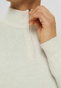 Helle Creme Quarter-Zip Pullover mit ribbeltem Kragen und Bündchen, aus einem weichen Stoff gefertigt, mit glatter Textur und minimaler Ausstattung.