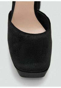 Čierna semišová topánka na vysokom podpätku s uzavretou špičkou a platformovou podrážkou. Hladká textúra s minimálnym šitím a zakriveným zadným dizajnom.