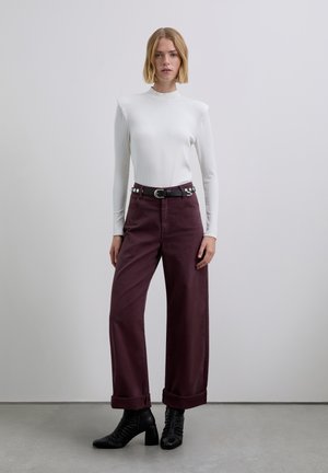 Biały prążkowany top z długim rękawem połączony z bordowymi spodniami o szerokich nogawkach, wywiniętymi mankietami i czarnym paskiem z srebrnymi okuciami. Czarne botki na obcasie.