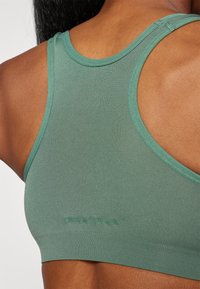 Grøn sport BH med en tekstureret overflade, der har en rund hals og racerback-design. Mærkenavnet "ONLY PLAY" trykt nær bunden.