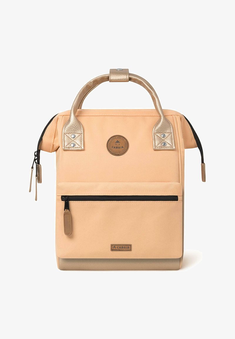 Pfirsichfarbene Canvas-Tasche mit goldenen Akzenten, Tragegriff, vorderer Reißverschlusstasche und Markenlabel. Sie verfügt über eine glatte Textur und ein strukturiertes Design.