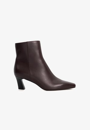 Bottine en cuir marron avec un bout pointu élégant et un talon bloc de hauteur moyenne. Texture lisse, coutures minimales et design moderne.