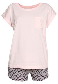 Lichtroze t-shirt met een ronde hals en korte mouwen, gecombineerd met zwart-witte shorts met een zigzagpatroon.