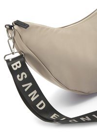Beige Nylon Tasche mit geschwungenem Design, ausgestattet mit einem schwarzen Griff mit der Aufschrift "SAND" und einem silbernen Reißverschluss.