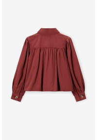 Chemise en coton rouge à manches longues avec col à patte boutonnée, détails froncés dans le dos et poignets boutonnés. Texture lisse et coupe décontractée.