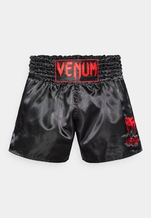 Pantalones cortos de boxeo de satén negro con cintura elástica, con un logo bordado en rojo en el centro y un gráfico en la pierna izquierda.