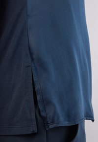 Marineblauwe, kortelang mouw shirt met een gladde textuur, voorzien van een zijsplit aan de zoom en rechte stiksels langs de randen.