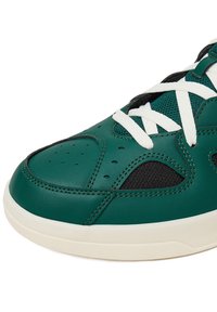 Grüner und schwarzer Sneaker aus glattem Leder und Mesh, mit weißen Schnürsenkeln, perforierter Zehenkappe und einer leichten, off-white Sohle.