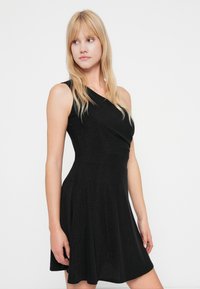 Rochie neagră cu un singur umăr, cu un corp strâns și fustă evazată, realizată dintr-un material texturat care reflectă lumina. Finisaj neted, fără embellishments vizibile.