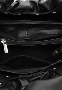 Wnętrze czarnej skórzanej torby z miękką podszewką, wieloma zamykanymi na zamek przegrodami oraz detalem z logo marki. Gładka tekstura i elegancki design.