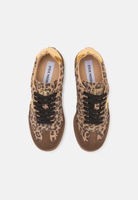 Sneakers with a leopard print upper, brown suede accents, and black laces. Features a gold logo tag and light-colored lining. Flat sole design.