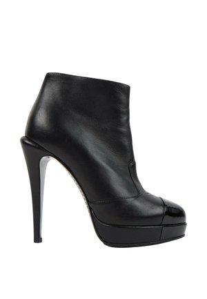 Bottine noire en cuir à talon haut avec embout brillant et semelle plateforme, vue de profil extérieur sur fond blanc.