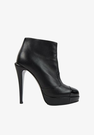 Bottine noire en cuir à talon haut avec embout brillant et semelle plateforme, vue de profil extérieur sur fond blanc.