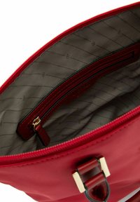 Innenansicht einer roten Lederhandtasche mit weichem Stofffutter, das eine Reißverschlusstasche und dekorative Nähte aufweist. Sichtbare goldene Hardwareakzente.