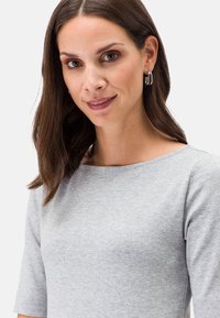 Graues Baumwoll-T-Shirt mit Rundhalsausschnitt und kurzen Ärmeln. Glatte Textur, minimalistisches Design und keine sichtbaren Muster oder Verzierungen.