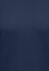 Gros plan sur la texture d'un tissu tricoté bleu marine montrant des mailles fines et régulières ainsi qu'une surface douce du matériau.