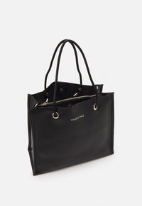 Bolso tote de cuero negro con dos asas largas, herrajes dorados, cierre de cremallera y logotipo grabado en la parte frontal. Forma rectangular con textura suave.