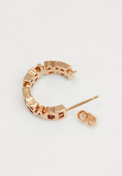 Gold-tone metal hoop earring with cut-out geometric patterns, featuring a straight post and a secure back closure.