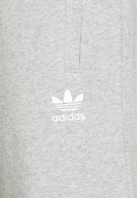Svetlošedý mikina s jemnou, textúrovanou látkou. Obsahuje malé biele logo Adidas na ľavej strane. Jednoduchý, nenápadný dizajn.