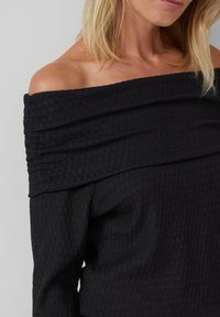 Schwarzes, schulterfreies Oberteil aus strukturiertem Stoff, mit einem drapierten Ausschnitt und gerippten Details, in einer taillierten Silhouette.