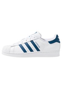 White leather sneaker with blue stripes and accents, featuring a rubber shell toe and textured sole. Lace-up design with logo details.