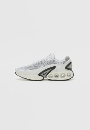 Chaussure de sport en mesh blanche avec des accents noir, bout arrondi, col rembourré et une semelle à bulle d'air unique avec trois sphères visibles.