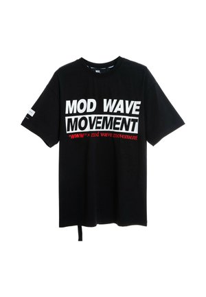 Joven con camiseta negra "Mod Wave Movement", shorts vaqueros con parche de oso, calcetines blancos con estampado y deportivas negras texturizadas, de pie sobre fondo blanco.