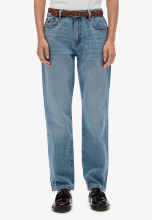 Lichtblauwe denim jeans met een relaxte pasvorm, rechte snit, vijf zakken en een gevlochten bruine leren riem. Ook gekleed met bruine schoenen.