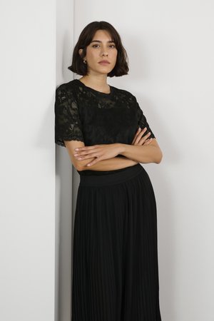 Black lace top with short sleeves, featuring a floral pattern. Paired with a pleated black skirt and an elastic waistband.