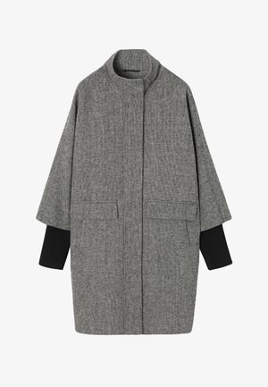 Pelēks un melns houndstooth mētelis ar augstu apkakli, platām piedurknēm, divām priekšējām kabatām un ribotiem adījuma aproces akcentiem. Struktūrēts, pārspīlēts dizains.
