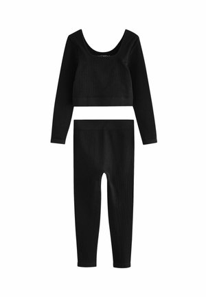 Musta ribbed crop-top, jossa on pitkät hihat ja matching korkea vyötärö leggings. Ominaisuuksina kaarrellu pääntie ja teksturoitu kangas koko matkalla.