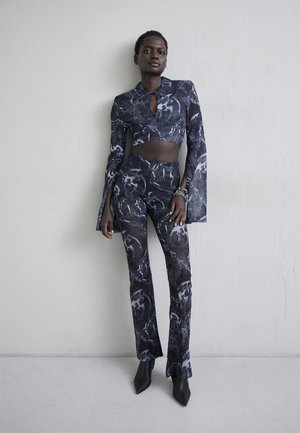 Σαλοπέτα δύο τμχ που περιλαμβάνει ένα κομμένο, μπλουζάκι με γιακά και μακρύ μανίκι, καθώς και εφαρμοστά παντελόνια με αφηρημένο σχέδιο σε μαύρο και γκρι, κατασκευασμένο από ελαστικό υλικό.