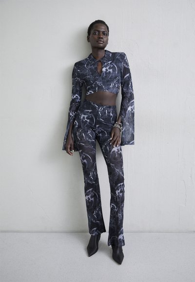 Ensemble deux pièces comprenant un haut long à manches longues, cropped avec col et un pantalon ajusté avec un motif abstrait noir et gris, fabriqué à partir d'un matériau extensible.