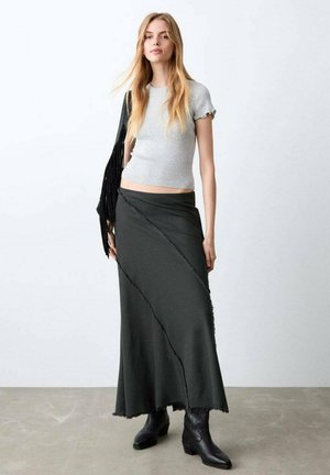 Top gris acanalado de manga corta combinado con una falda larga gris oscuro con costuras diagonales y bordes deshilachados, complementado con botas negras hasta el tobillo.