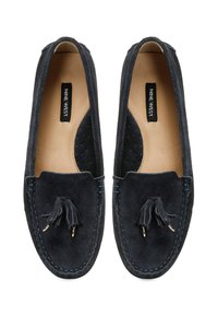 Mocassins en suède bleu marine avec un gland décoratif, des coutures bleues contrastées et des accents perforés noirs de chaque côté. Semelle plate, bout rond.