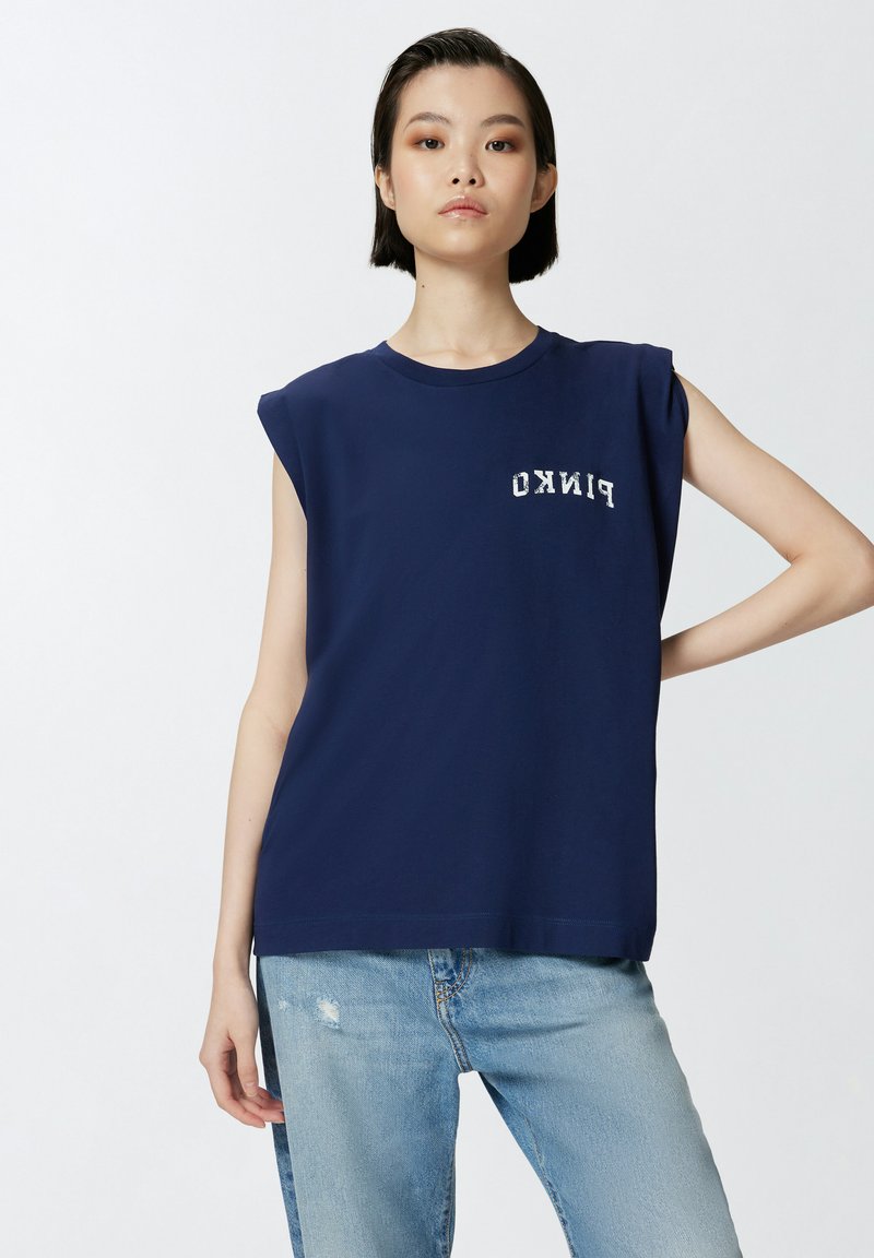 Mornarska majica bez rukava od pamuka s okruglim izrezom i printom logotipa. Uparen s svijetloplavim iznošenim trapericama.