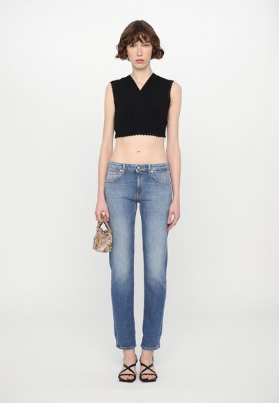 Black cropped top with scalloped edges, light blue straight-leg jeans, and black strappy sandals; accessory is a small floral-patterned handbag.